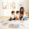 Children engaging with the pink Activity Wall Busy Board, featuring a xylophone, clock, and various sensory activities.