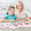 Children engaging with the pink wooden Activity Wall Busy Board, featuring a xylophone, clock, and various sensory.