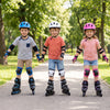 Three kids wearing adjustable inline skates in a park, showcasing blue, white, and pink colors with safety gear.
