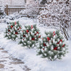Artificial cedar topiary ball trees with red berries and snow-covered foliage, ideal for winter outdoor decoration.