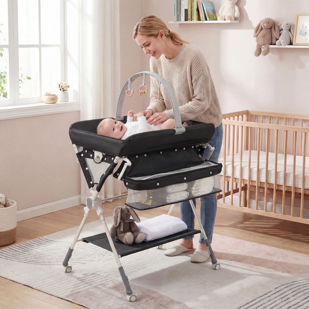 Foldable black baby changing table showcasing a side view with a removable toy bar and storage space for essentials.