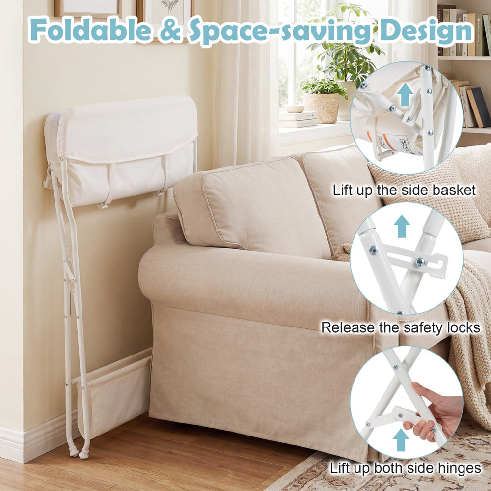 Foldable beige diaper changing table with side basket, safety belt, and height ruler for convenient baby care.