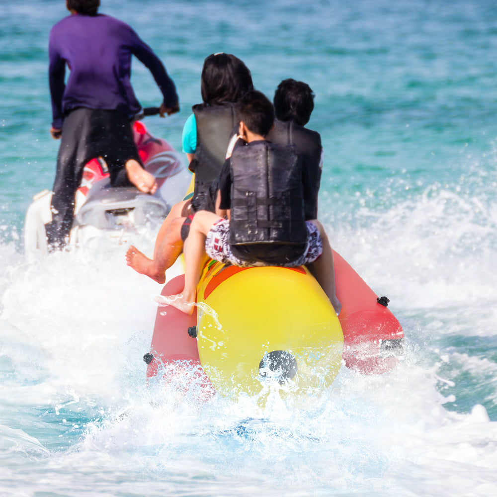Three-person inflatable banana boat in bright red and yellow, featuring non-slip seats and reinforced handles for.