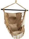 Hanging rope swing chair in beige with soft pillow and cushions, featuring elegant tassels for indoor or outdoor use.