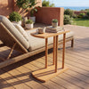 Narrow C-shaped teak wood side table with thickened top, perfect for outdoor use beside a lounge chair.