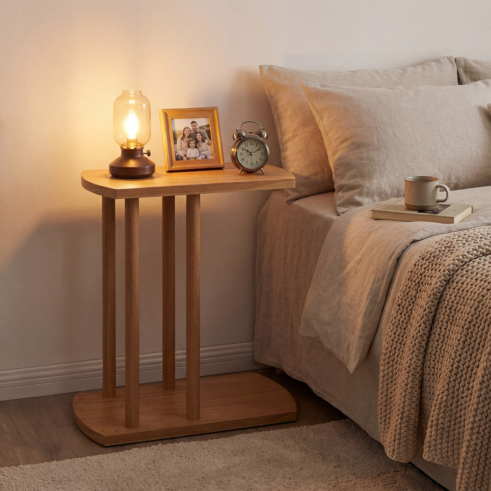 Narrow C-shaped teak wood side table with 2 tiers, sturdy base, and lamp, perfect for bedside or couch use.