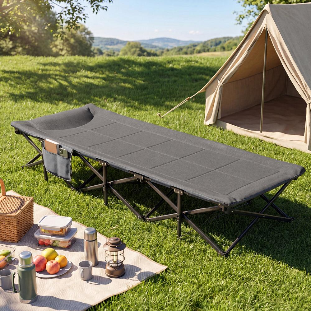 Camping cot in gray with a padded pillow and side storage pouch, ideal for outdoor travel and relaxation.