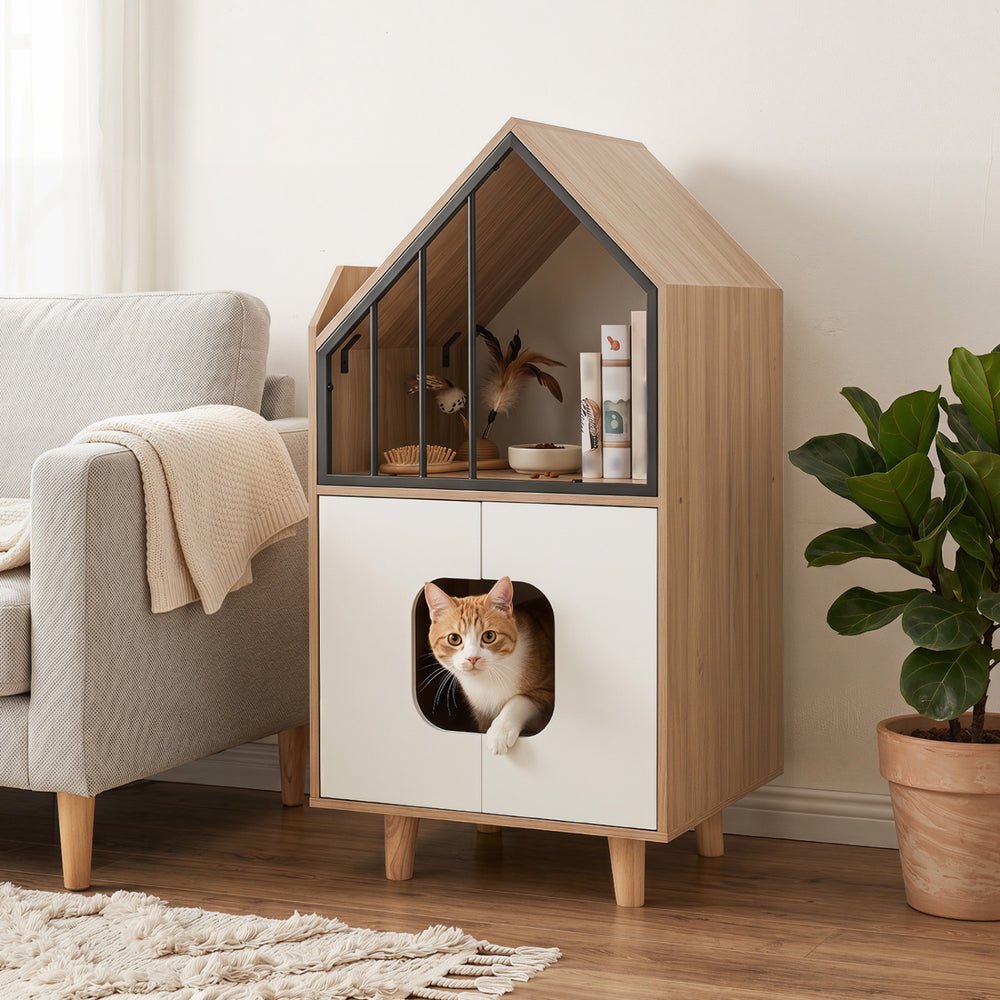 Modern cat litter box enclosure with house-shaped design, dual doors, and upper shelf for cat supplies in a living room setting.