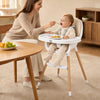 Convertible high chair in beige with beech wood legs, featuring a 5-point harness and removable double tray for easy feeding.