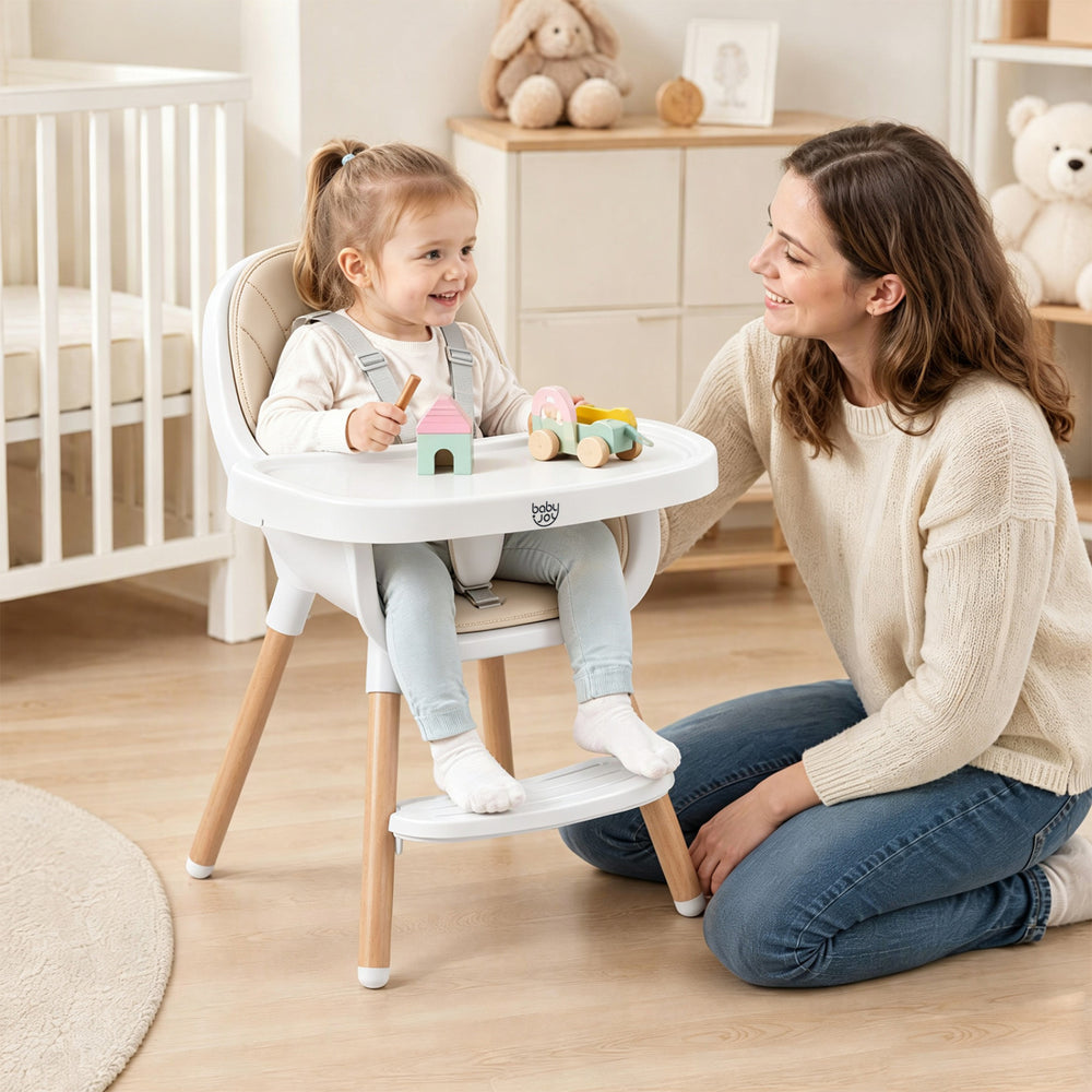 Convertible high chair in beige with a 5-point harness, featuring a removable tray and beech wood legs for stability.