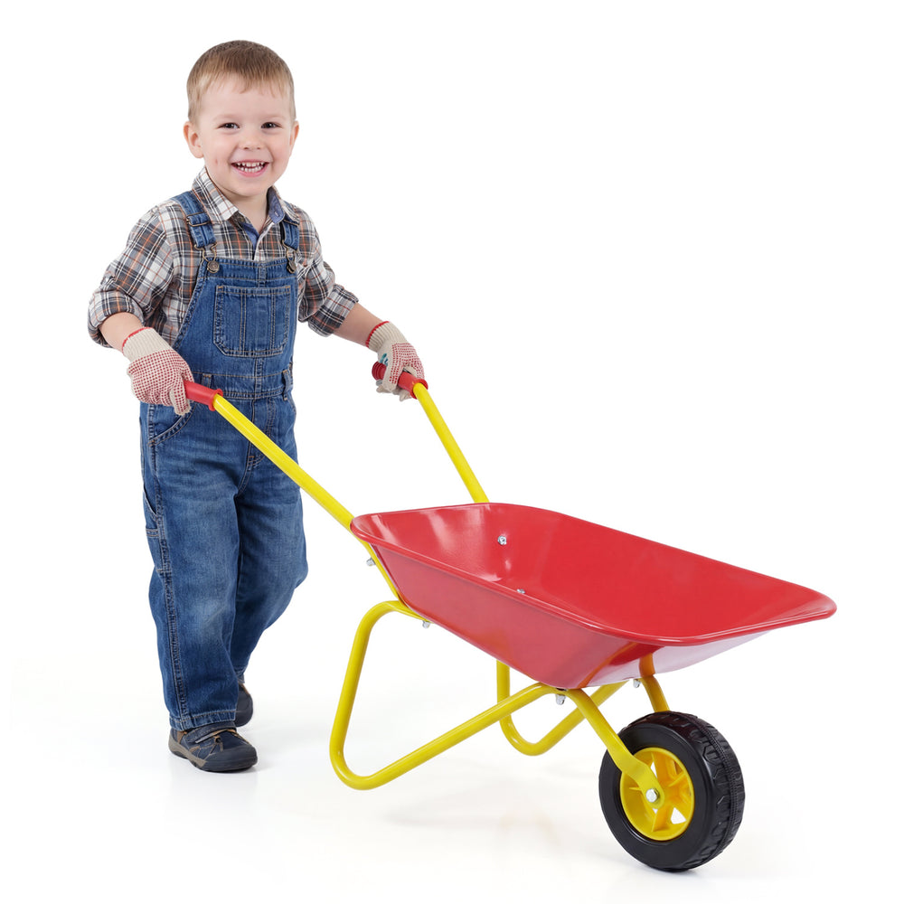 Child smiling while pushing a red kids wheelbarrow with all-terrain wheels, perfect for hauling toys and outdoor fun.