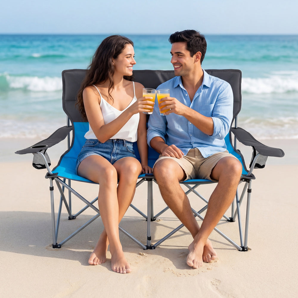 Double camping chair in blue with cup holders, featuring a sturdy frame and soft padding, perfect for beach relaxation.