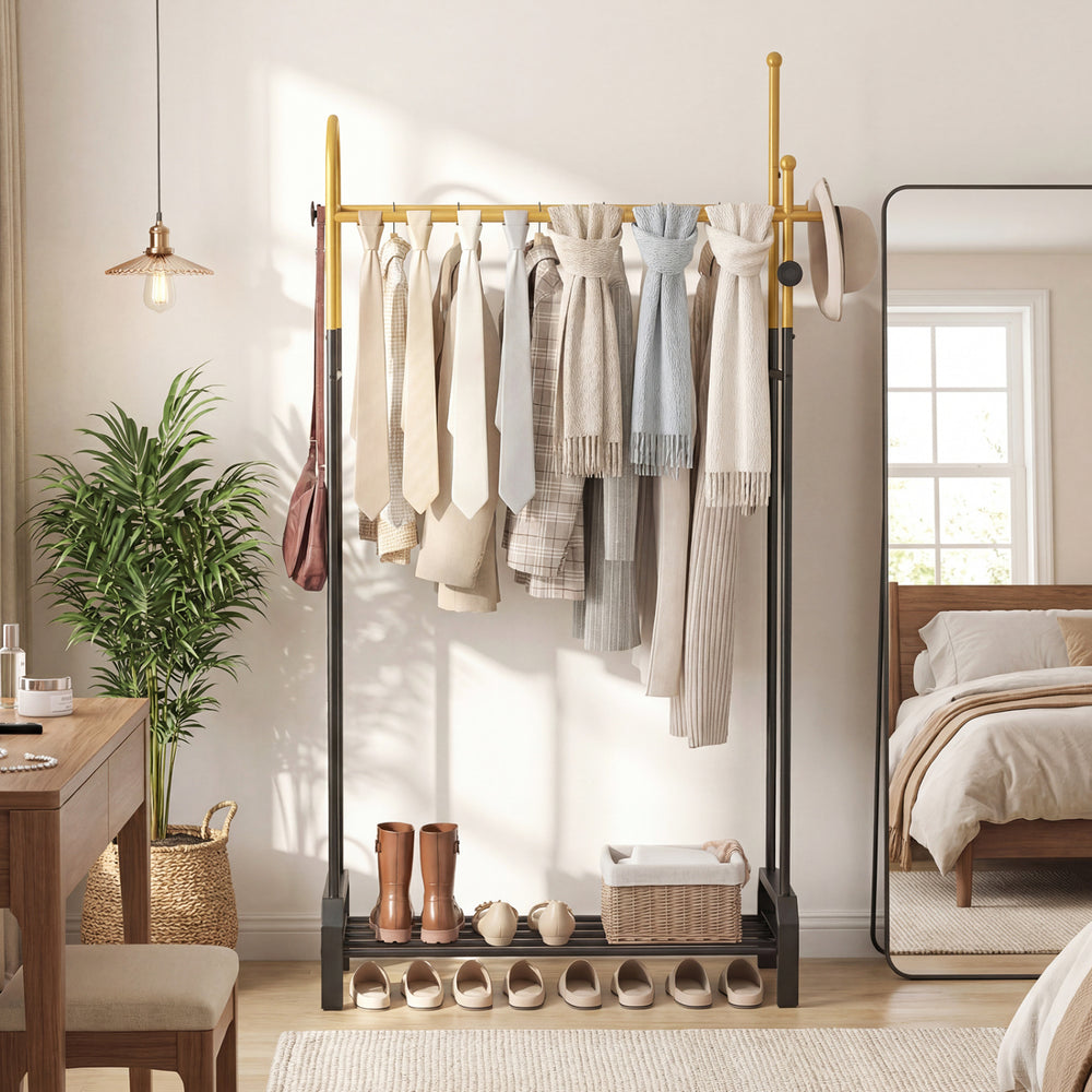 Double rods garment rack in gold and black with hanging clothes, side hooks, and a bottom shelf for shoes, ideal for.
