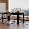 Black dining table with six folding chairs, featuring a griddle grill and smooth surfaces for easy cleaning.