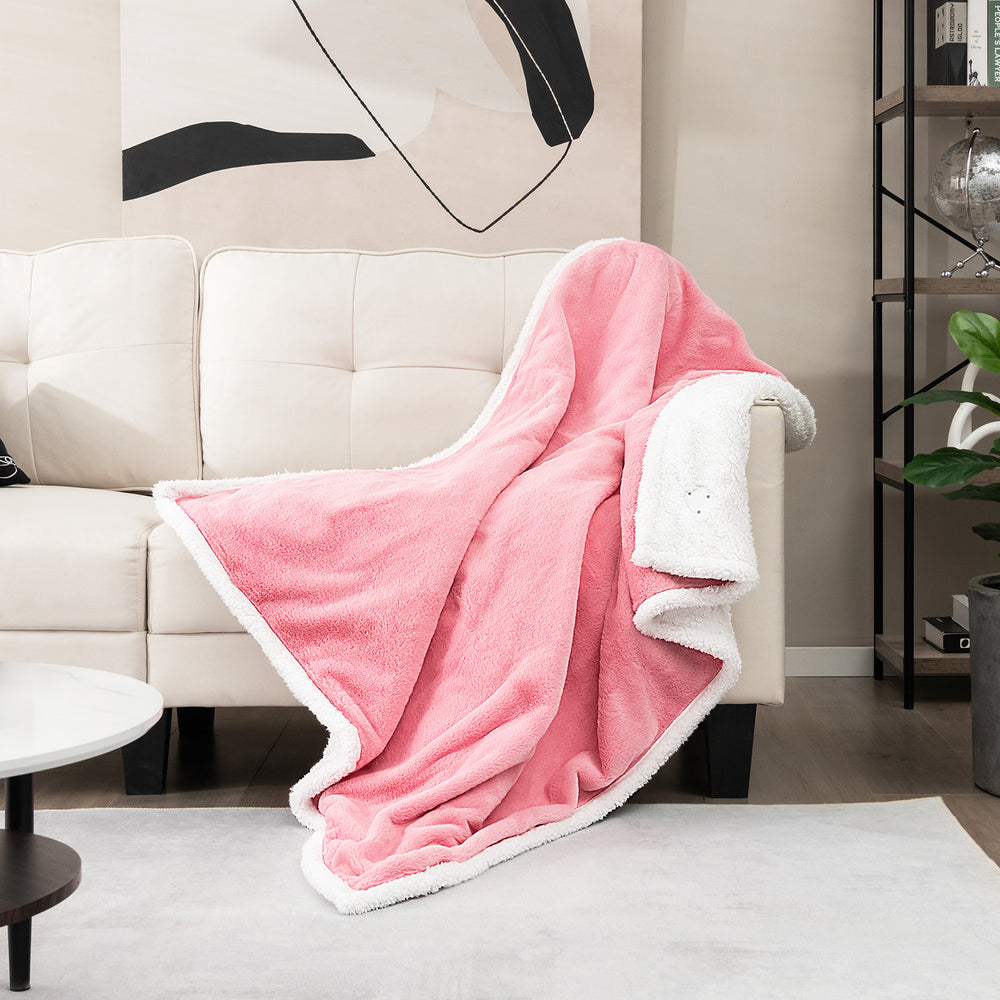 Cozy pink electric heated blanket throw draped over a sofa, featuring soft sherpa fleece for ultimate comfort.