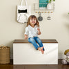 Flip-top storage chest in white with rustic brown lid, ideal for kids' toys and shoes, used as a bench.