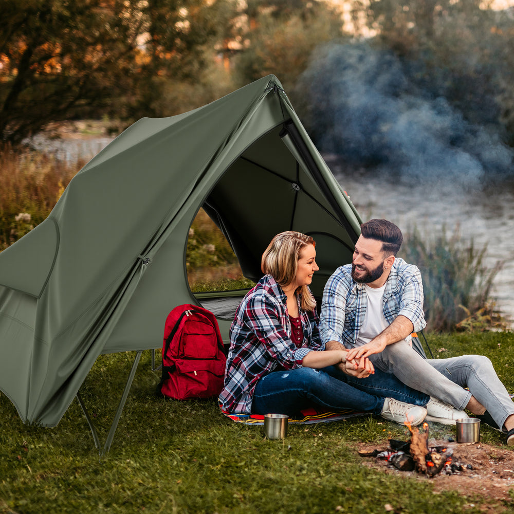 Foldable 2-person camping cot tent in green, set up by a lake, perfect for outdoor adventures and camping trips.