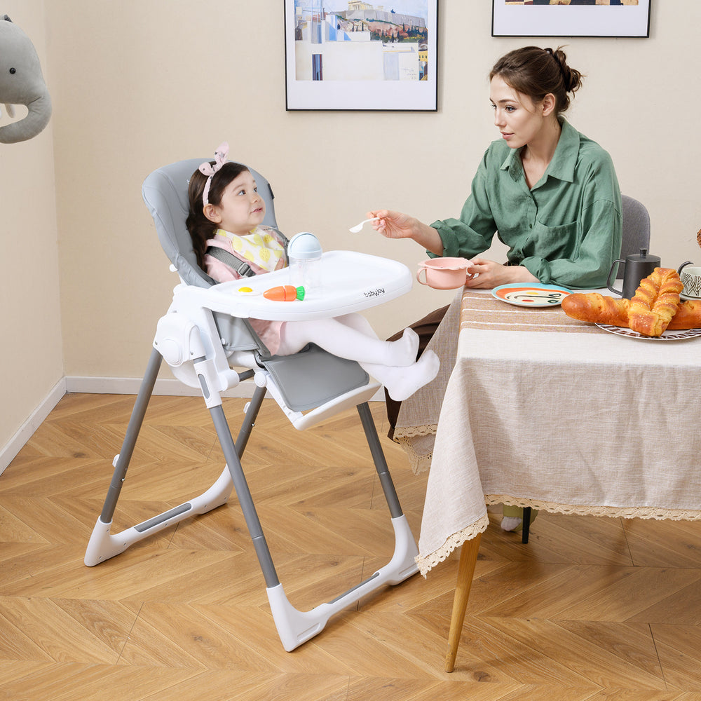 Foldable baby high chair in light gray with adjustable height and reclining seat, perfect for mealtime comfort.