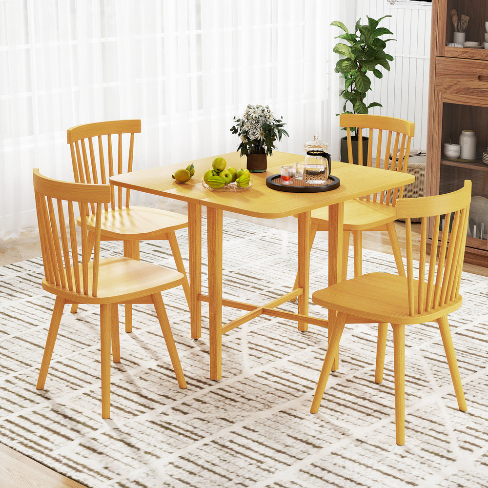 Foldable dining table with rubber wood legs, featuring drop leaf panels, set for four in a bright, modern space.