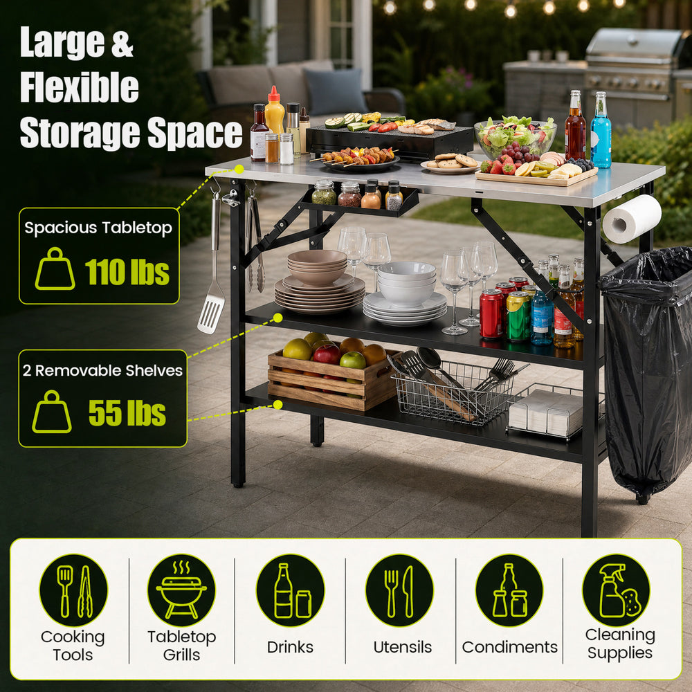 Foldable outdoor cook station with stainless steel top, removable shelves, and trash bag holder for camping convenience.