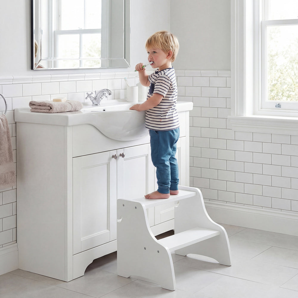 Toddler using the foldable white 2-step stool at a bathroom sink, featuring side chalkboards for creative fun.