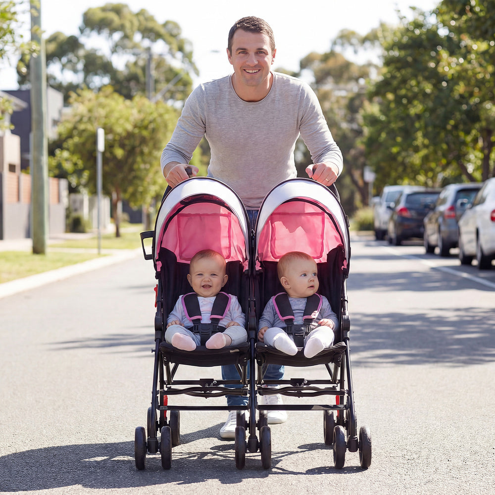 Foldable twin baby double stroller in pink, featuring a lightweight frame and 360-degree swivel wheels for easy travel.