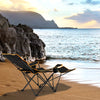 Folding camping chair with footrest, adjustable backrest, and cup holder, perfect for outdoor relaxation by the beach.