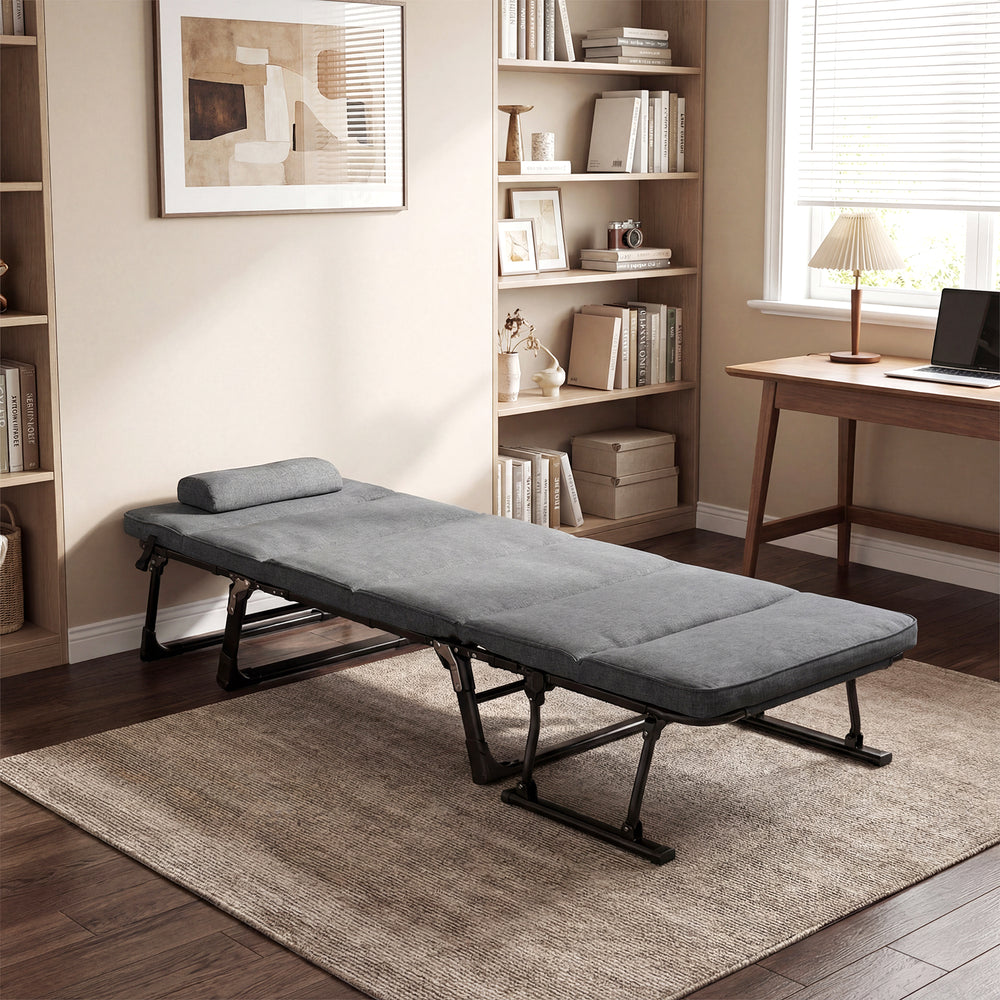 Gray folding camping cot in a living room setting, featuring a removable cushion and tri-fold design for easy storage.