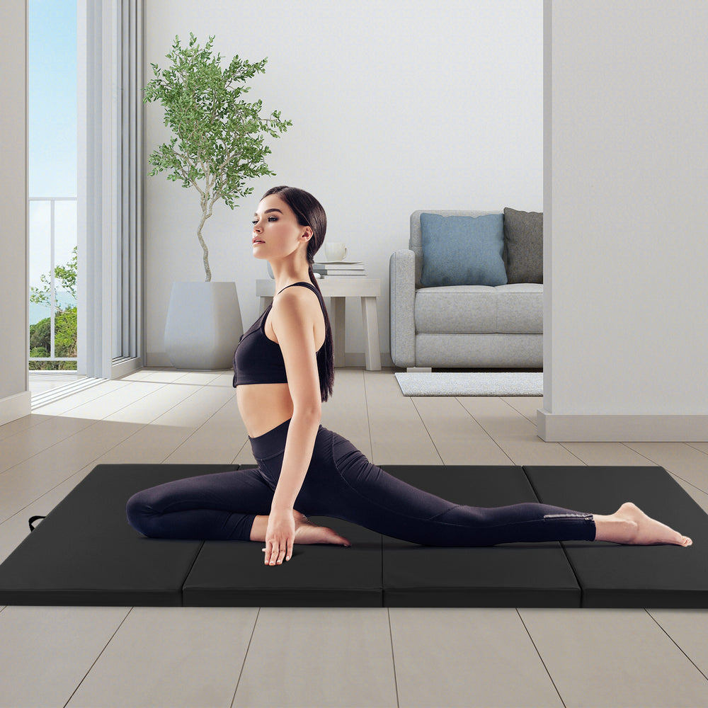 Black 4-panel folding exercise mat with carrying handles, ideal for stretching and gymnastics in a modern living space.