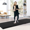 Black 4-panel folding exercise mat with carrying handles, ideal for gymnastics and stretching, shown in a home setting.