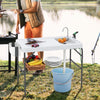 Folding fish cleaning table with sink and faucet, featuring a spacious tabletop and side trash bag holder for BBQ use.