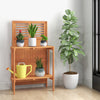 Folding garden potting bench with teak oil finish, featuring 2-tier storage shelves for plants and tools in a stylish.