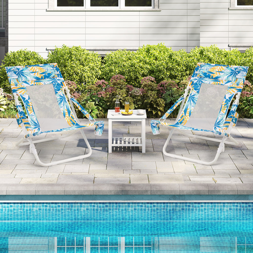 Two blue folding low beach chairs with padded head pillows and a small table, perfect for relaxing by the pool.