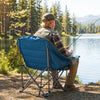 Oversized blue camping chair with side pockets and cup holder, perfect for outdoor relaxation by the lake.