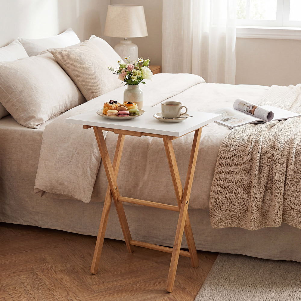 Folding TV tray table in white with bamboo structure, perfect for small spaces in bedrooms or living rooms.