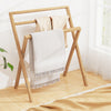 Freestanding foldable teak wood towel rack with three crossbars, ideal for drying towels in any room.