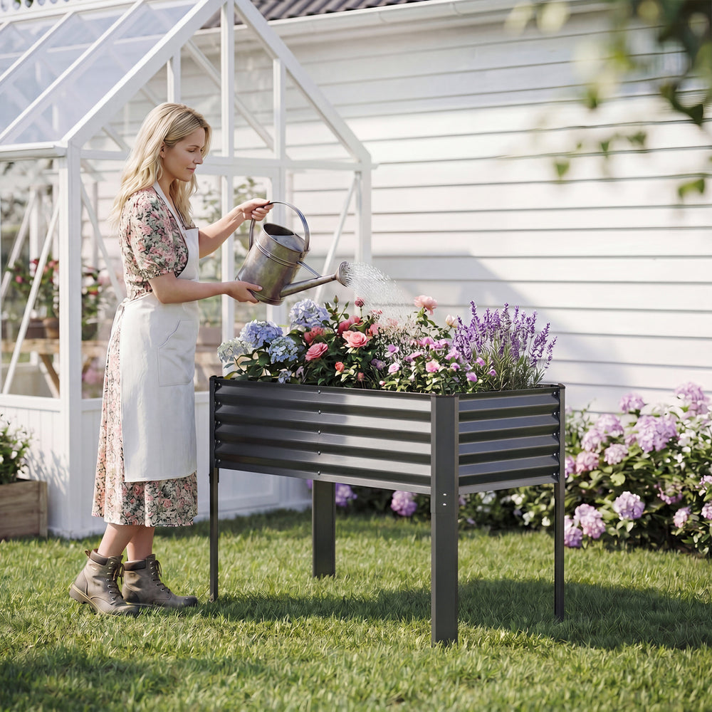 Galvanized raised garden bed with legs, 46" x 24" x 31", ideal for planting flowers and vegetables in a backyard.