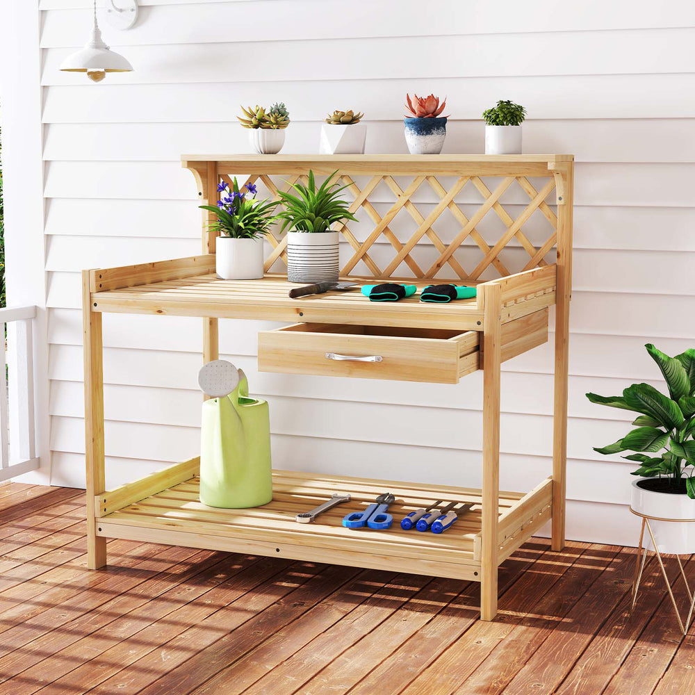 Wooden garden potting bench with lattice trellis, spacious countertop, slide-out drawer, and lower shelf for plant.
