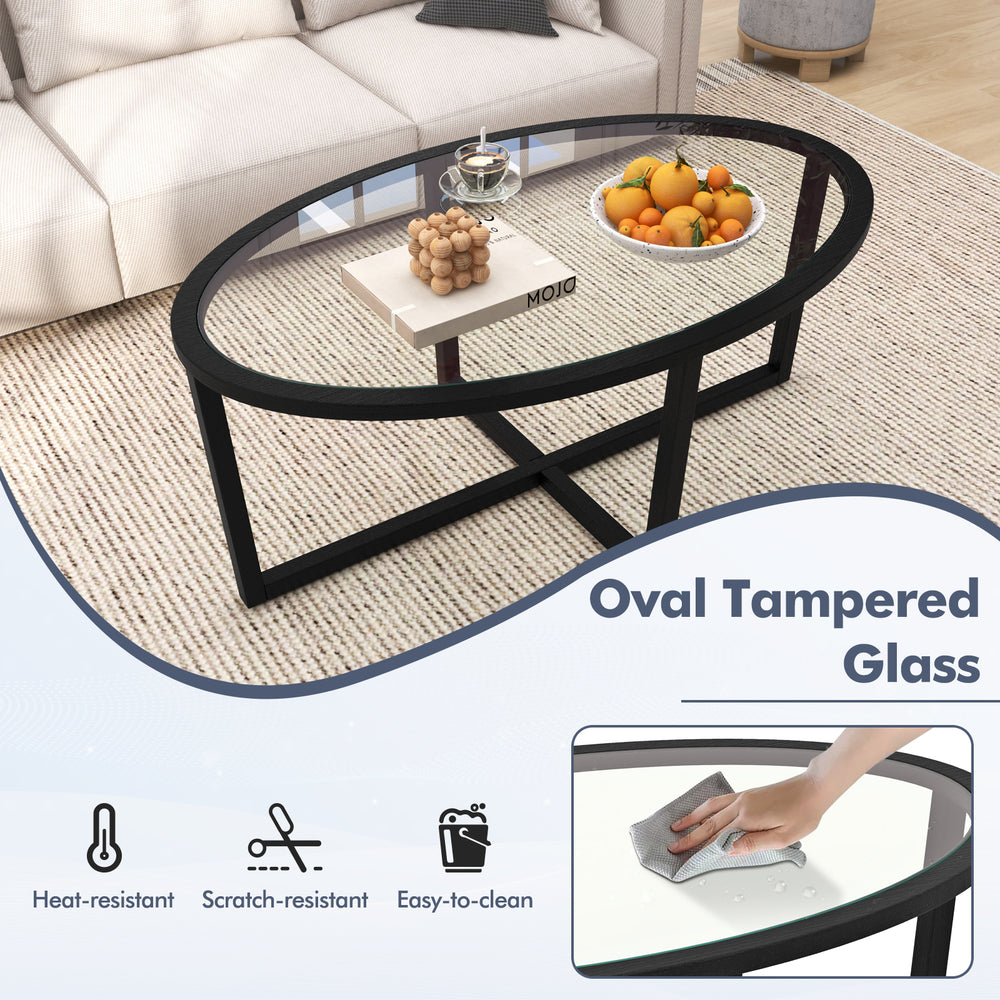 Oval tempered glass coffee table with black acacia wood legs and cross base, perfect for living room decor and.