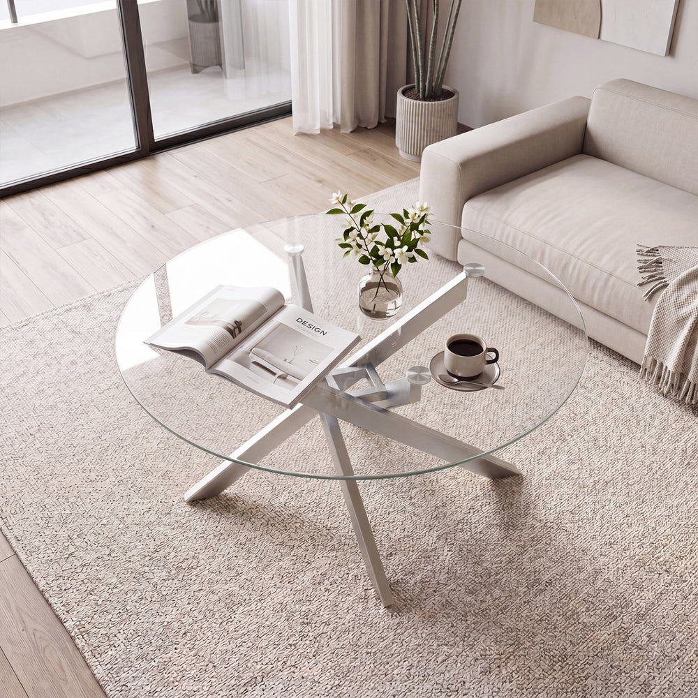 Round glass coffee table with a silver geometric frame, featuring a tempered glass top for modern living room decor.