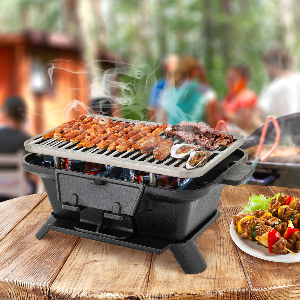 Compact cast iron hibachi grill with adjustable height grate, perfect for grilling meats and vegetables outdoors.
