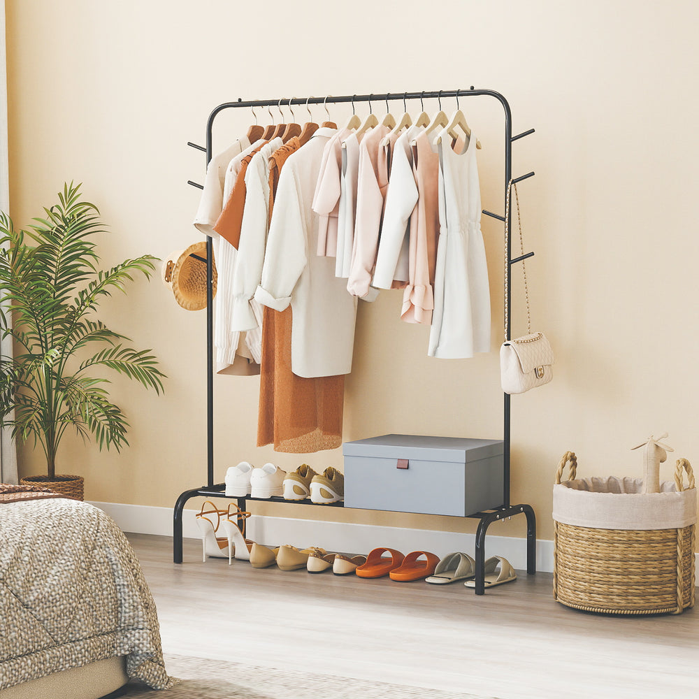 Heavy duty black metal clothes rack showcasing hanging garments and stylish tree branch patterns, perfect for bedroom.