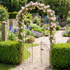 Heavy-duty bronze metal garden arch with gate, featuring floral trellis for climbing plants, ideal for outdoor events.