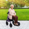 Height adjustable purple rollator walker with seat, featuring all-terrain wheels, used by a senior in a park setting.