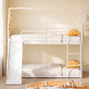 House-shaped metal twin over twin low bunk bed in white with cozy bedding and decorative fairy lights for children's.