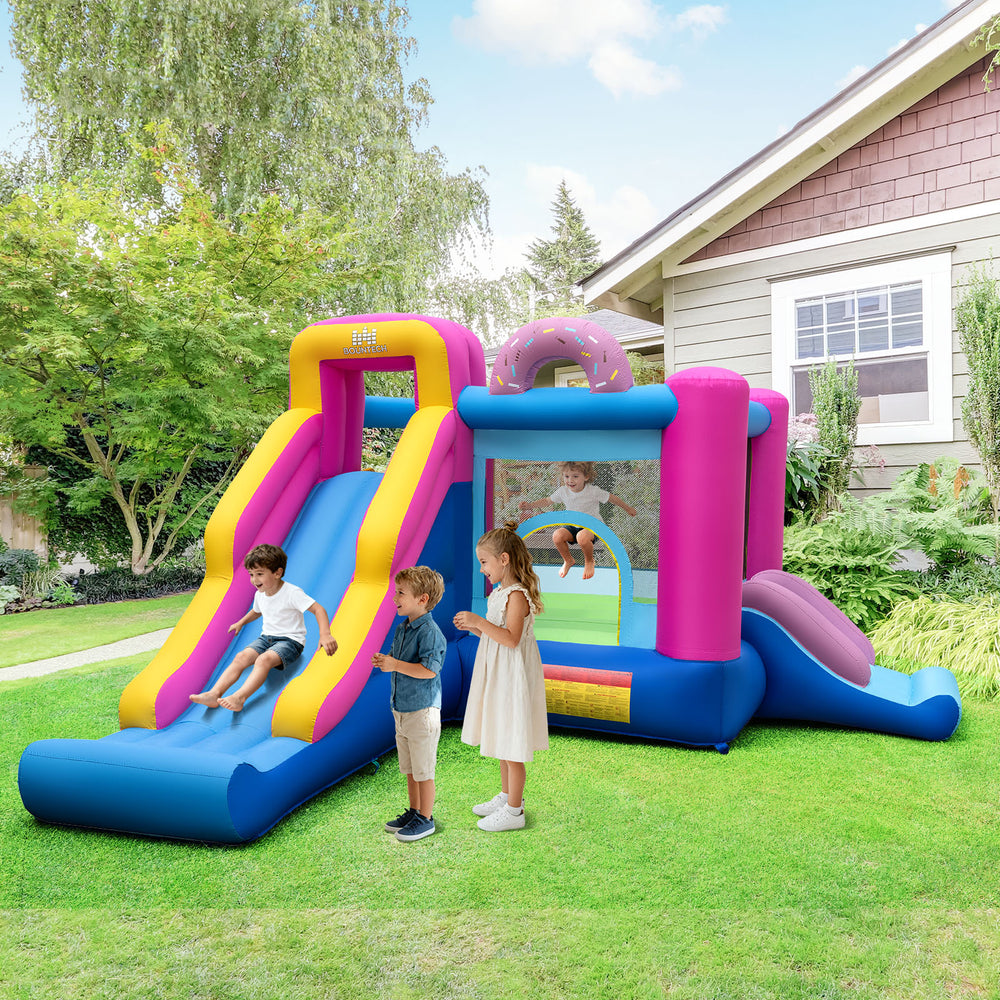 Inflatable bounce house with slides and basketball hoop, featuring a doughnut theme for backyard fun and active play.