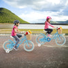 Two kids riding a 14-inch blue bike with training wheels and front basket, perfect for outdoor fun and balance training.