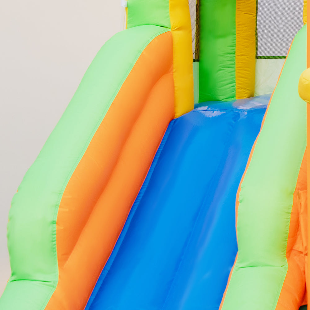 Brightly colored inflatable water slide with dual surfing slides and a climbing wall, perfect for summer yard fun.