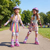 Two kids wearing pink roller skates with light-up wheels, enjoying outdoor skating in a park.