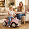 Kids sit-to-stand vehicle in pink with working steering wheel and under-seat storage, perfect for indoor playtime.